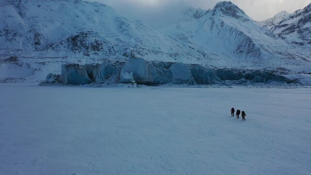 Aerial Drone View of Three Mountaineers Trekking Across Laigu Glacier in Tibet with Snow Mountains and Blue Ice