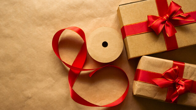 Christmas gift boxes with red ribbon and copy space top view. Flat lay composition of holiday presents on craft paper background, winter seasonal celebration workshop banner template.