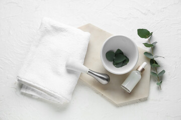 Mortar and pestle with eucalyptus branch and bottle of essential oil on white background © Pixel-Shot