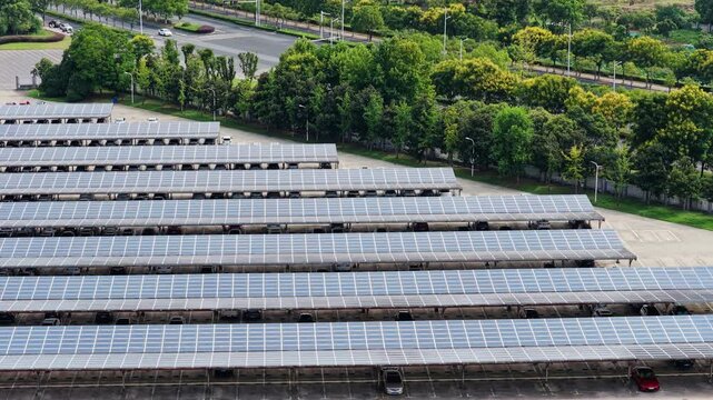 Shifting aerial perspective of solar carports and roadside trees