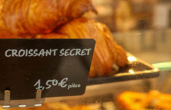 Croissant secret sign with price in euro at a french bakery window, indicating a special pastry in paris