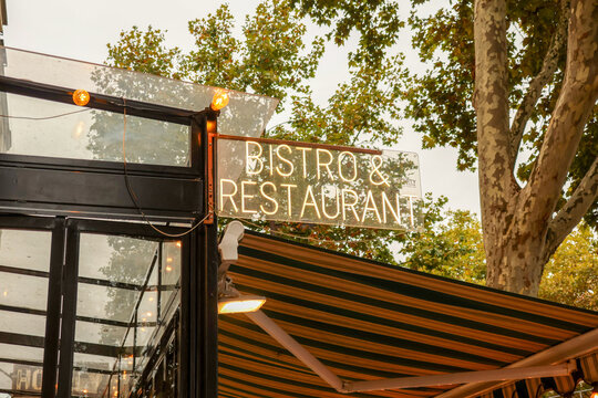 Bistro and restaurant neon sign glowing above an outdoor awning in paris, inviting tourists to experience french cuisine and cafe culture