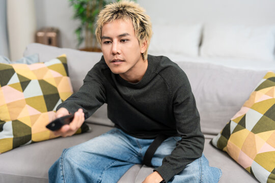 Asian attractive man watching movie on television in living room at home. 