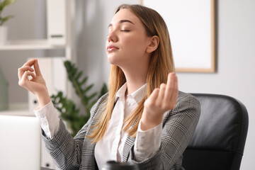 Young businesswoman meditating at table in office. Balance concept