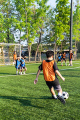 Fototapeta premium Young school children dribbling football on outdoor soccer field. 