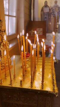 Many burning candles stand on an altar in a church. Religious ceremony, prayer time, and devotion concept. Slow motion footage.