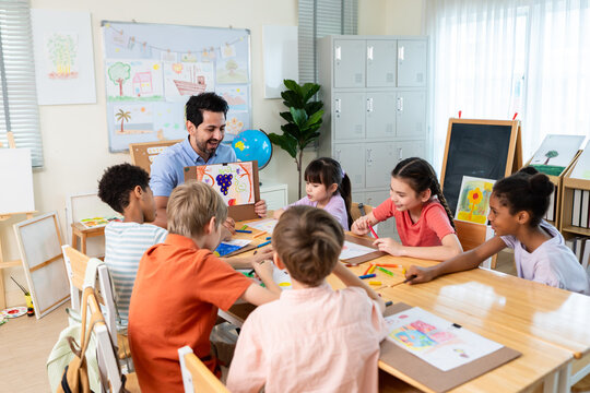 Caucasian male teacher teaching art lesson to children in classroom. 