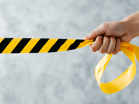 Hand Pulling Black and Yellow Hazard Tape