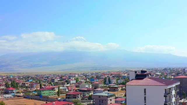 Drone hovers above Dogubayazit rooftops with Mount Ararat and high plains beyond, supporting city panorama media, urban geography, tourism promotion and regional identity in eastern Turkey.