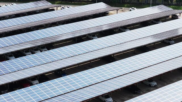 Lateral aerial view across solar carport roofs and parked cars
