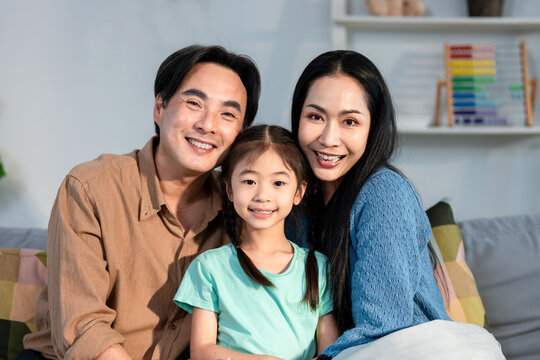 Portrait of Asian family sit together on sofa in living room at home. 