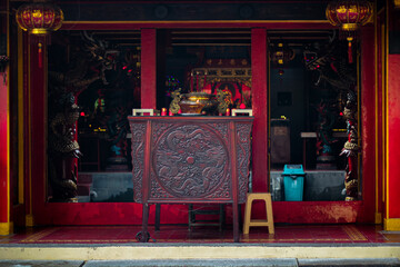 An ornate carved wooden offering table stands prominently at the entrance of a vibrant Chinese Buddhist or Taoist temple © obby