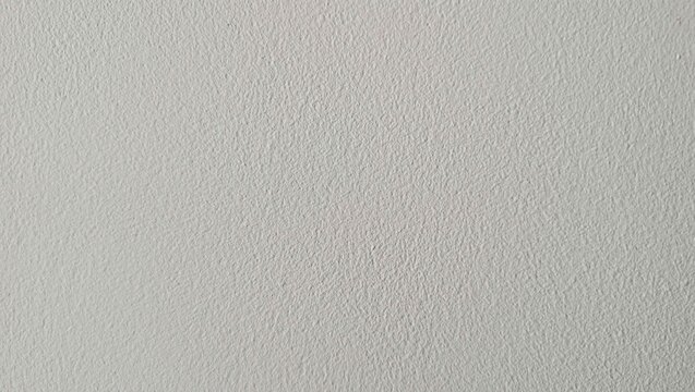 Surface texture of light gray wall with slight patterns seen in simple indoor setting during bright daylight