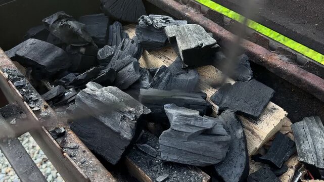 Stirring Charcoal Briquettes in Outdoor Barbecue Grill with Metal Poker, Arranging Hot Coals for Fire Ignition and BBQ Cooking