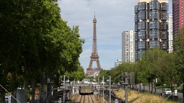 Eiffel Tower landmark standing above urban railway lines with city buildings and trees