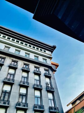 Low Angle Perspective of a Modern Gray Architectural Building Fa&ccedil;ade against a Clear Blue Sky