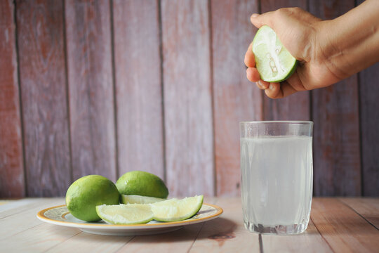 Squeezing lime juice into a glass with lime slices