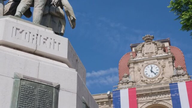 Close-up of a Hotel de Ville facade with a clock tower and large French tricolor banners, Cannes, France