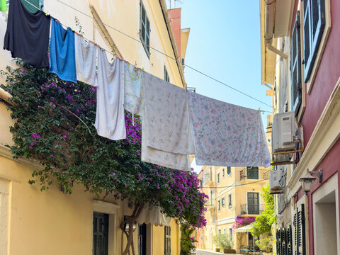 Laundry Lines Over Narrow Alley in Corfu Old Town, Greece, with Bougainvillea and Shutters