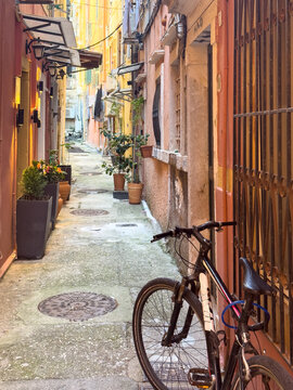 Bicycle beside potted plants in narrow Corfu Old Town alley, with weathered buildings, Corfu, Greece