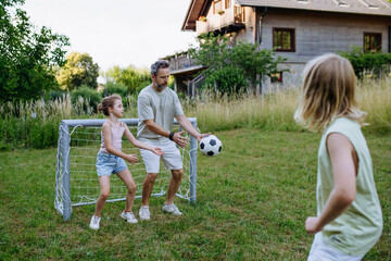 Obraz premium Father and kids playing football in backyard during summer afternoon.