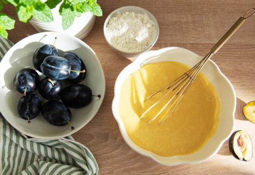 Baking plum cake ingredients with batter and flour