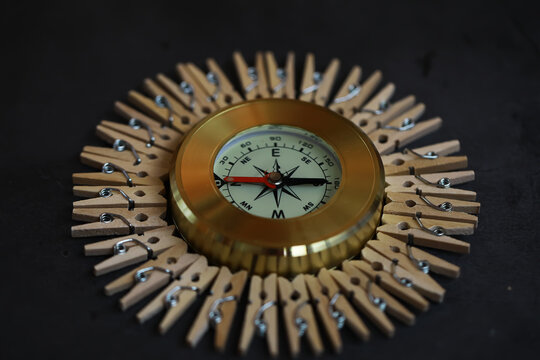 Creative Circular Arrangement of Compass and Clothespins on Dark Background