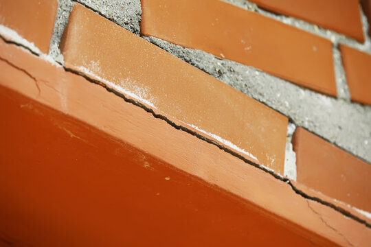 Close-Up of Red Brick Wall with Visible Cracks and Weathered Surfaces