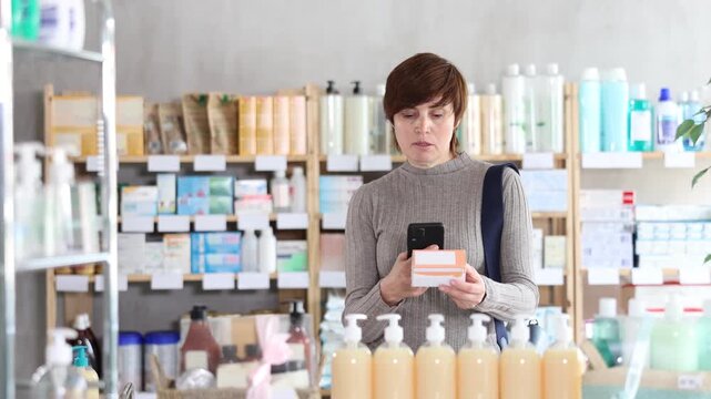 Woman in autumn clothes scans code on package of pills to check the expiration date . High quality 4k footage
