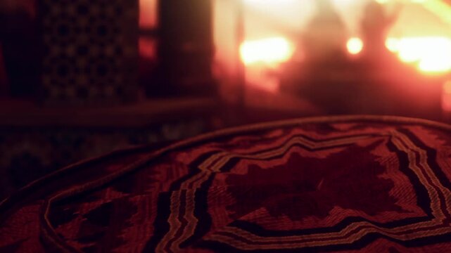 A close view of a traditional carpet placed on a surface in a Moroccan room. The soft glow of warm light surrounds the space, creating an inviting atmosphere at night.