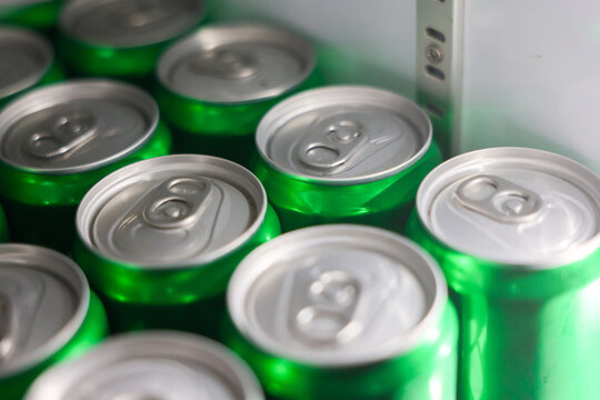 Green aluminum beverage can close packaging arrangement silver pull tab with soft reflection, metal drink container group in cooler, selective focus