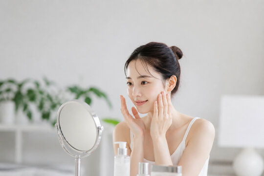 鏡の前で顔をケアするスキンケア美女