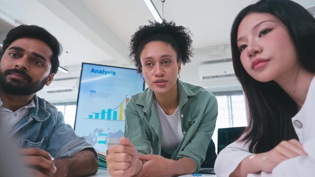 Close up of three corporate professionals gathering around a digital tablet, looking seriously at the screen to solve a problem and discuss business strategy.