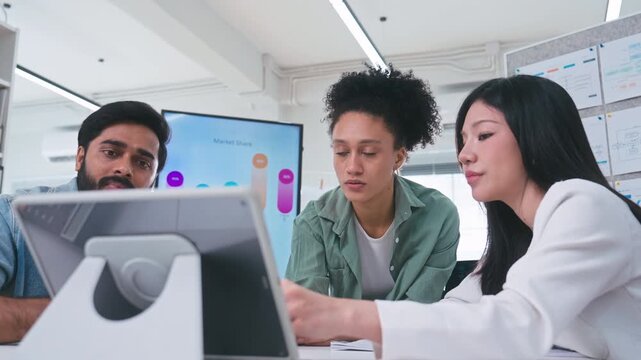Three corporate professionals gathering around a digital tablet, looking seriously at the screen to solve a problem and discuss business strategy.