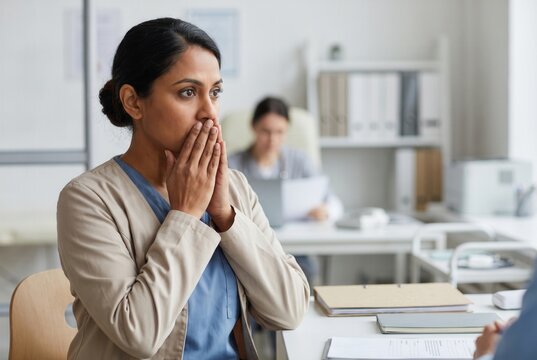 Young woman covering her mouth, reacting to bad news or a difficult diagnosis in a clinic
