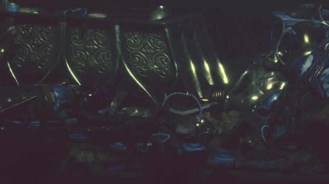 A dark underwater scene shows a treasure chest overflowing with gold coins and various artifacts. Small particles float around as light highlights the items.
