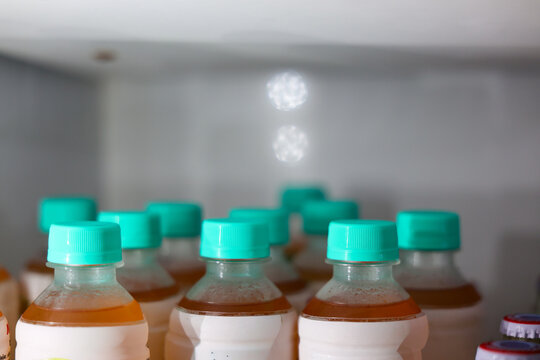 Plastic bottle, orange drink, turquoise cap, refrigerator shelf, beverage storage with chilled drink container in neat row inside cold appliance