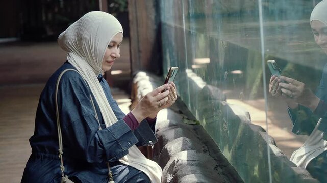 Woman using smartphone by aquarium glass