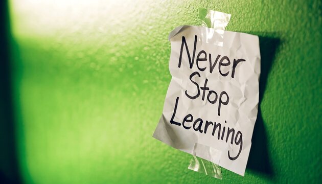 Crumpled paper note with the text never stop learning taped to a bright green wall