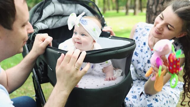 Mother and father gently push baby stroller. Baby rests peacefully in car seat. Pedestrian cross is visible nearby. Scene portrays calm, everyday parenting moment