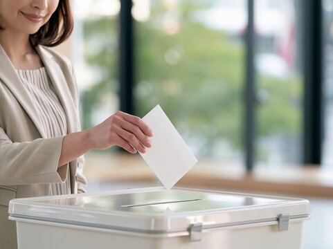 明るい投票所で女性が真剣な表情で投票用紙を投票箱に滑り込ませる手元