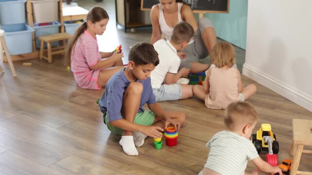 6 year boy plays with toys in front of other children in a kindergarten . High quality 4k footage