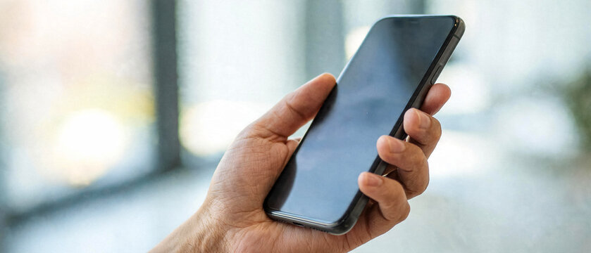 Close-up of a person's hand holding a sleek black smartphone with a dark screen, showcasing modern mobile technology.