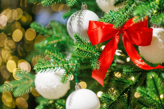 Red bow on Christmas tree with festive golden lights