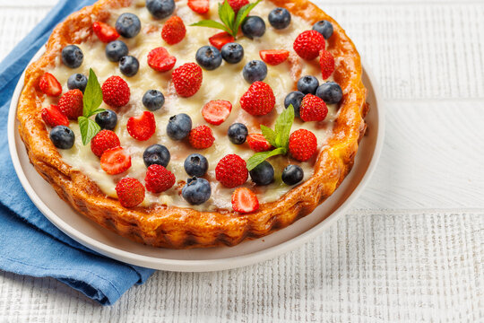 Homemade berry tart topped with fresh raspberries and blueberries