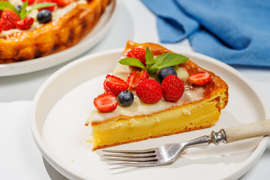 Slice of berry tart served on plate beside whole pie