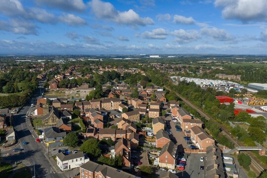 Aerial view over Castleford in Yorkshire showing residential streets brick houses a railway line local buildings and industrial land surrounded by trees and open countryside in summer