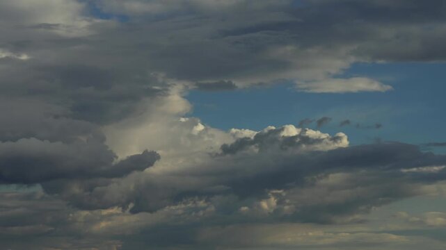 Time lapse of dramatic grey cumulus clouds rolling across a deep blue sky, capturing heavy multi layered grey and moving swiftly