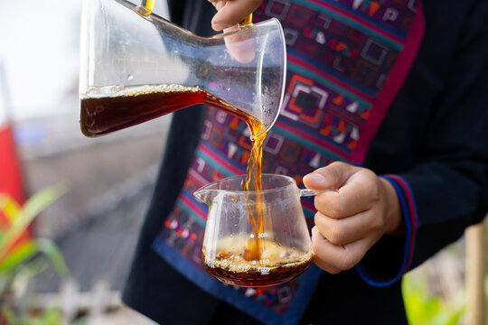 Coffee brewing pour glass server filter beverage aromatic hand cup Close view of fresh coffee poured from clear glass server into small cup, warm liquid flow, casual indoor cafe preparation scene