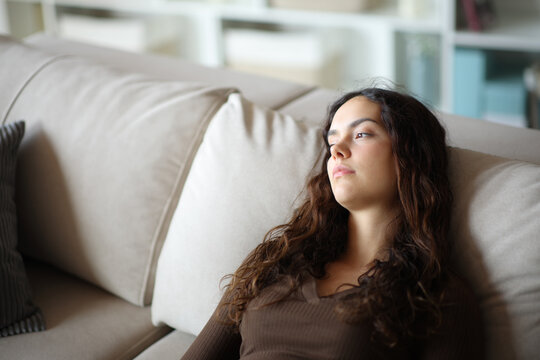 Apathetic teenage girl looking at side on a couch at home